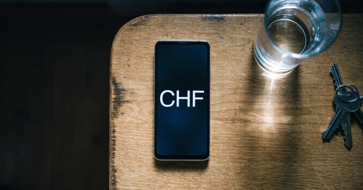 Ein Smartphone mit schwarzem Display liegt auf einem Holztisch neben einem Glas Wasser und einem Schlüsselbund.