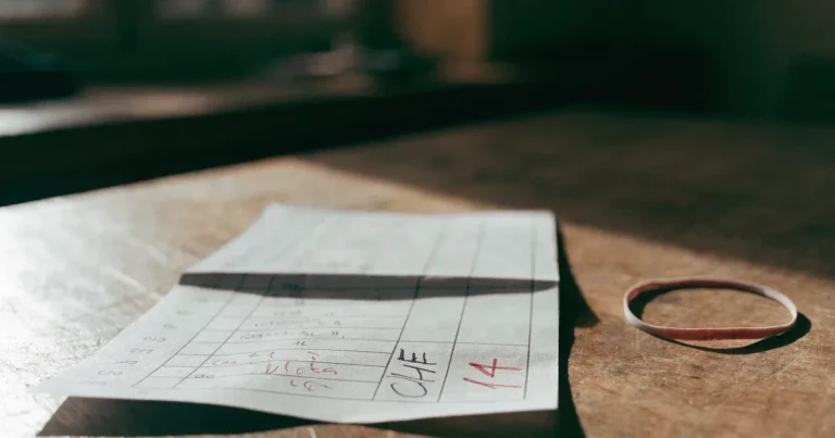 Ein Stapel unbeschriebener Papierzettel mit einem Gummiband liegt auf einer Werkbank im Seitenlicht