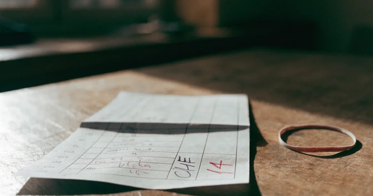 Ein Stapel unbeschriebener Papierzettel mit einem Gummiband liegt auf einer Werkbank im Seitenlicht